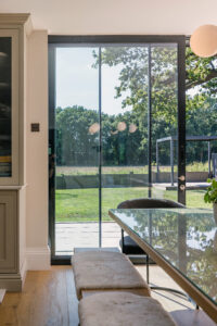 Flush threshold pocket sliders with slim aluminium frames in contemporary Cotswolds kitchen extension