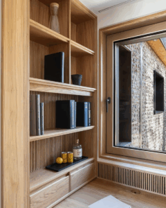 Oak interior detail showcasing Internorm alu-clad window and bespoke shelving, highlighting warm timber tones and architectural glazing integration.